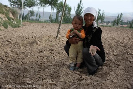 Ma Delan, aged 62, stands holding her grandchild. The land in her small village of Nanping is left fallow because of dry earth and drought conditions. Drought is one of the most harmful natural hazards in Northwest China. Climate change has a significant