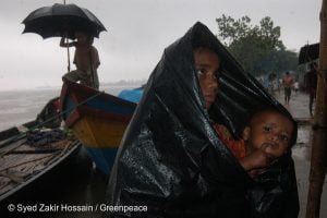 <p>A woman with her child waits for relief in heavy rain. Local people have lost their homes and jobs as a result of the floods. The floods were caused by the change in the course of the waterway on the river Jamuna.</p>