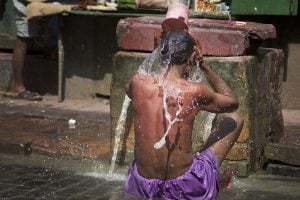 <p>Man taking a bath from a Kolkata stand post water pipe. [image by Jorge Royan]</p>
