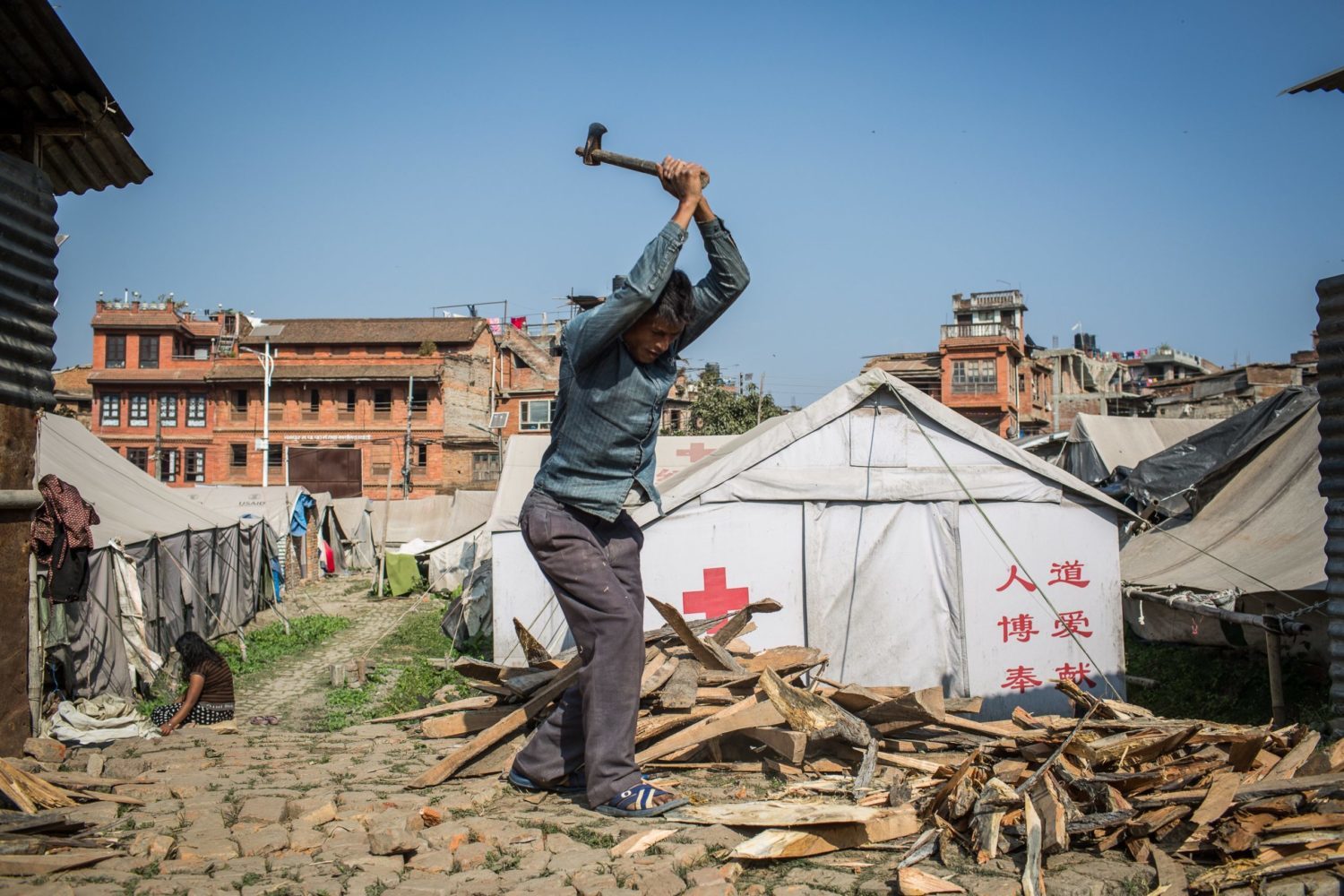 Bik Bahadur Shahi, an earthquake victim from Bhaktapur, chops firewood at a temporary camp where he and his family are still living.