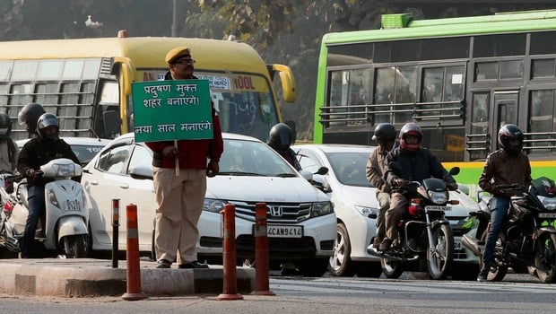 <p>A policeman holding a sign that reads, &#8220;make it a pollution free city, enjoy your new year&#8221; [image courtesy Delhi government]</p>
