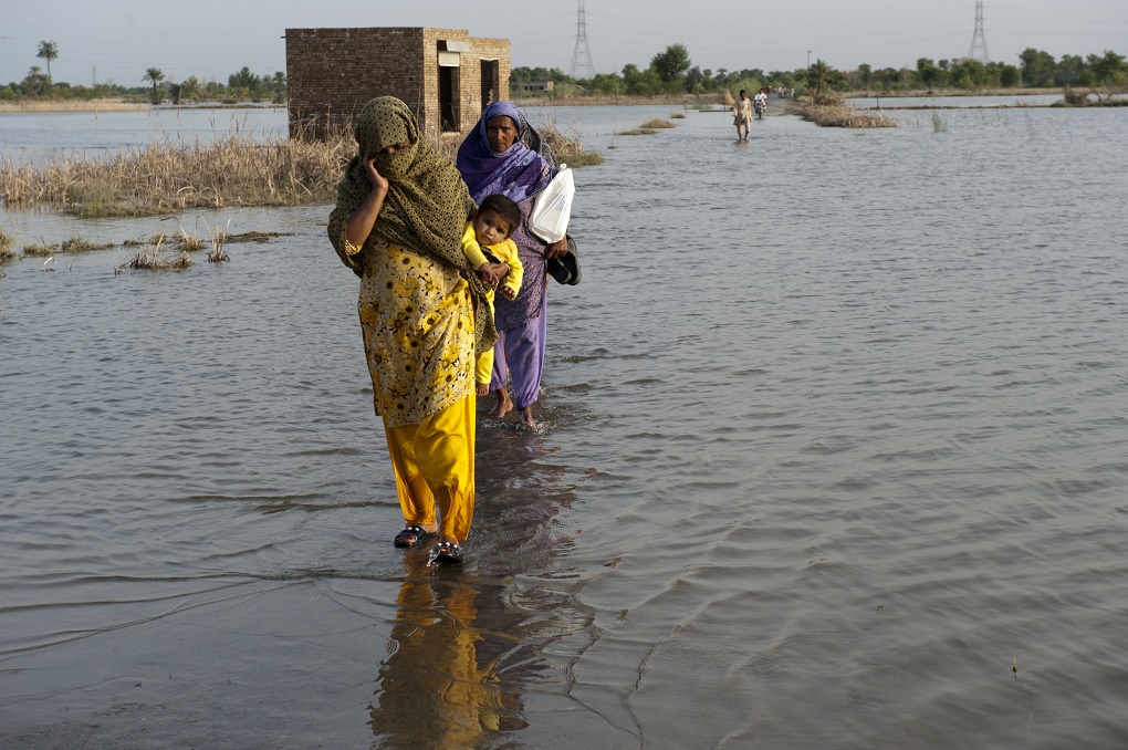 Pakistan's water crisis - Two women and a child walking through floods due to climate change