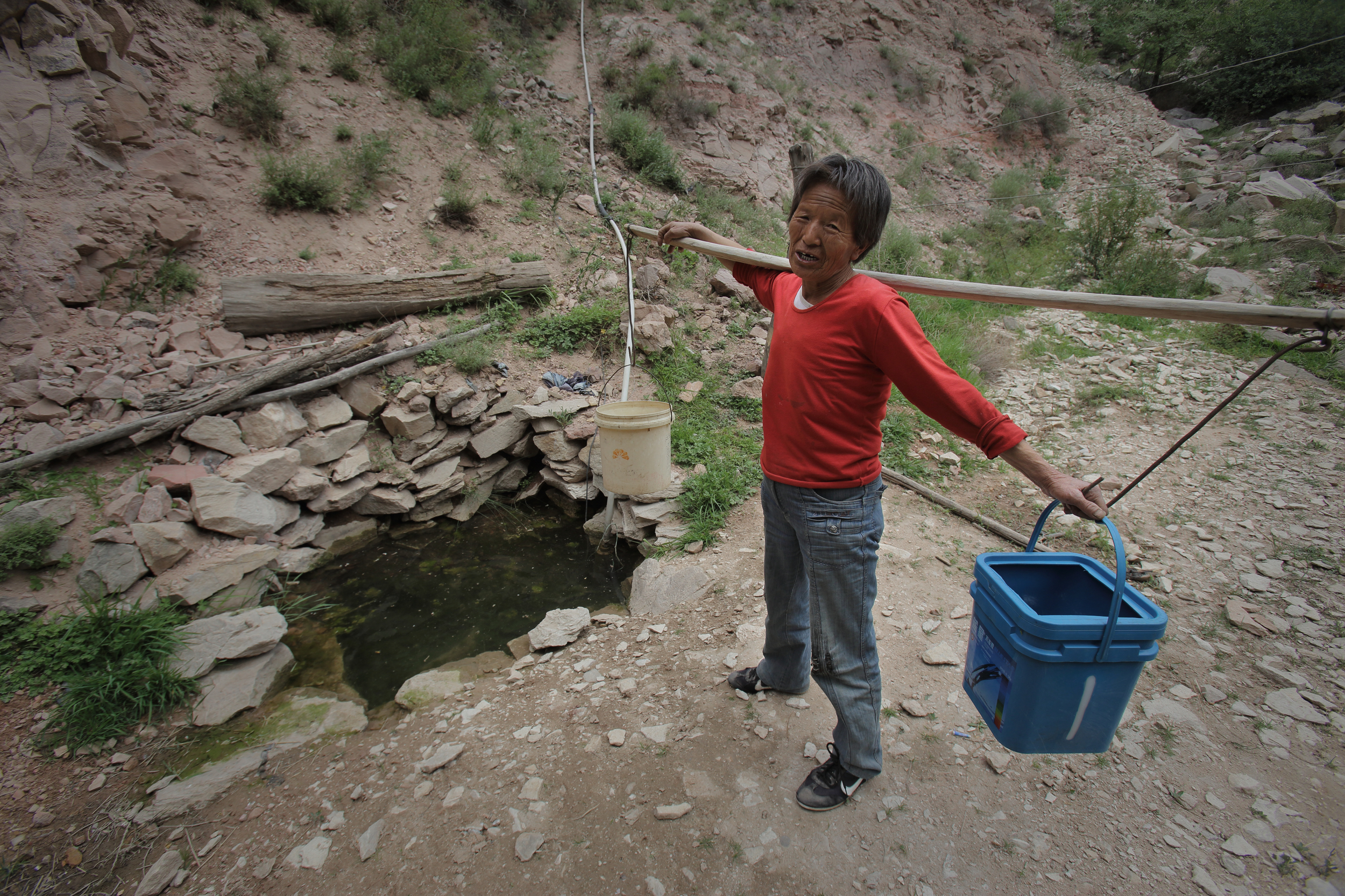<p>A woman collects water from a spring in a valley outside her village of Houjialiang in northwestern China, where coal mining has poisoned local rivers and streams (Image by Qiu Bo / Greenpeace)</p>