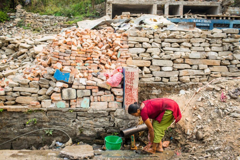 A women washes at a temporary tap near Arnoko Highway in Sindhupalchowck, Nepal. The original water spout was filled by debris during the quake. 