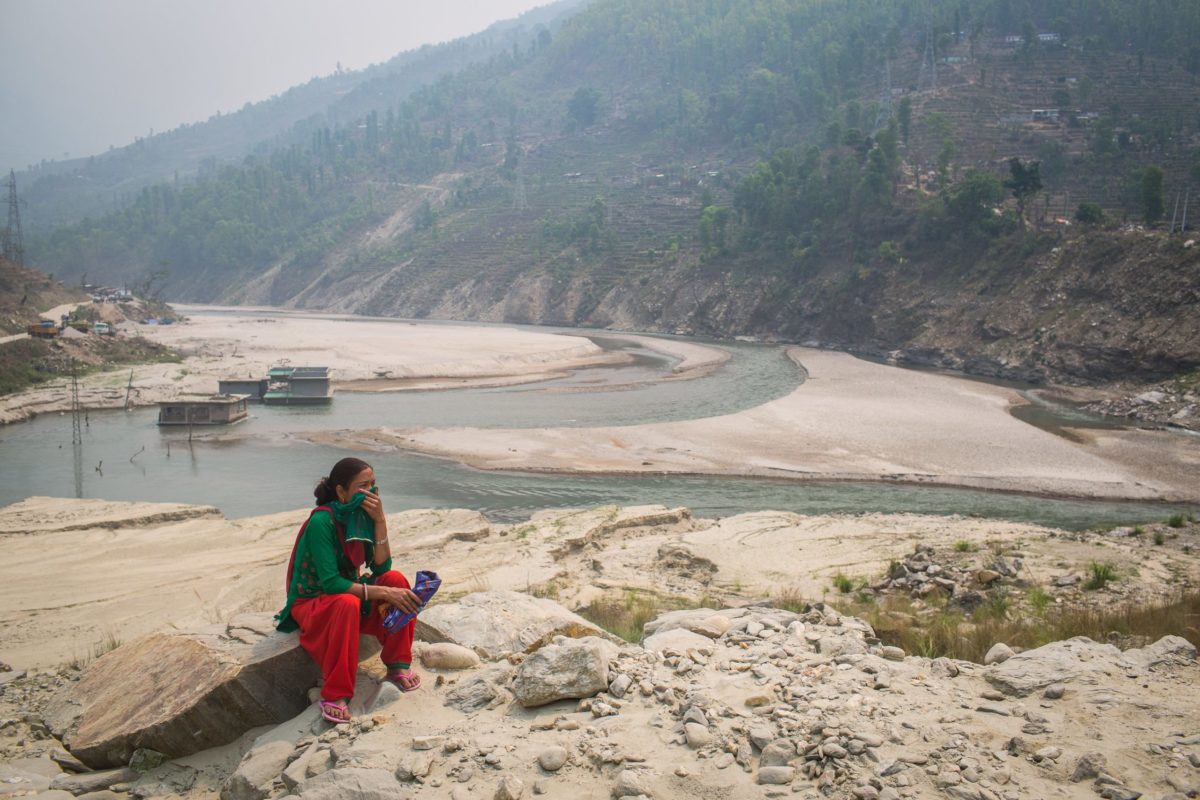 Laxmi Shrestha waits for bus on landslide debris on the bank of the Tamakoshi River. 
