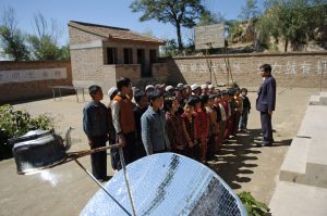 <p>Gansu province, China. Children assemble in school courtyard. Solar panel disc heats kettle. [image by Liang Qiang / World Bank]</p>