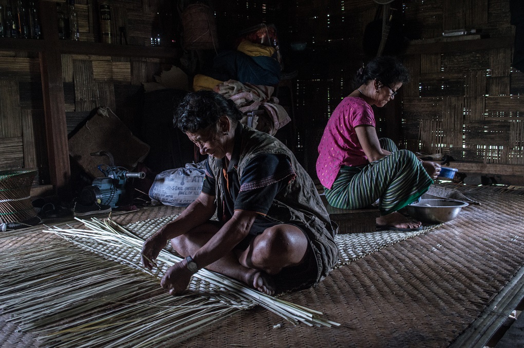<p>Buge Mena and his wife, Niriya Mena working at home, weaving and cleaning rice, respectively [image by: Sweta Daga]</p>