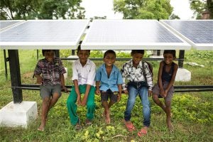 <p>Children sit under solar panels in India (Image by Greenpeace)</p>