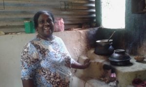 <p>A beaming Latha Dissanayake stands next to her improved kitchen stove [image by: Dilrukshi Handunnetti]</p>
