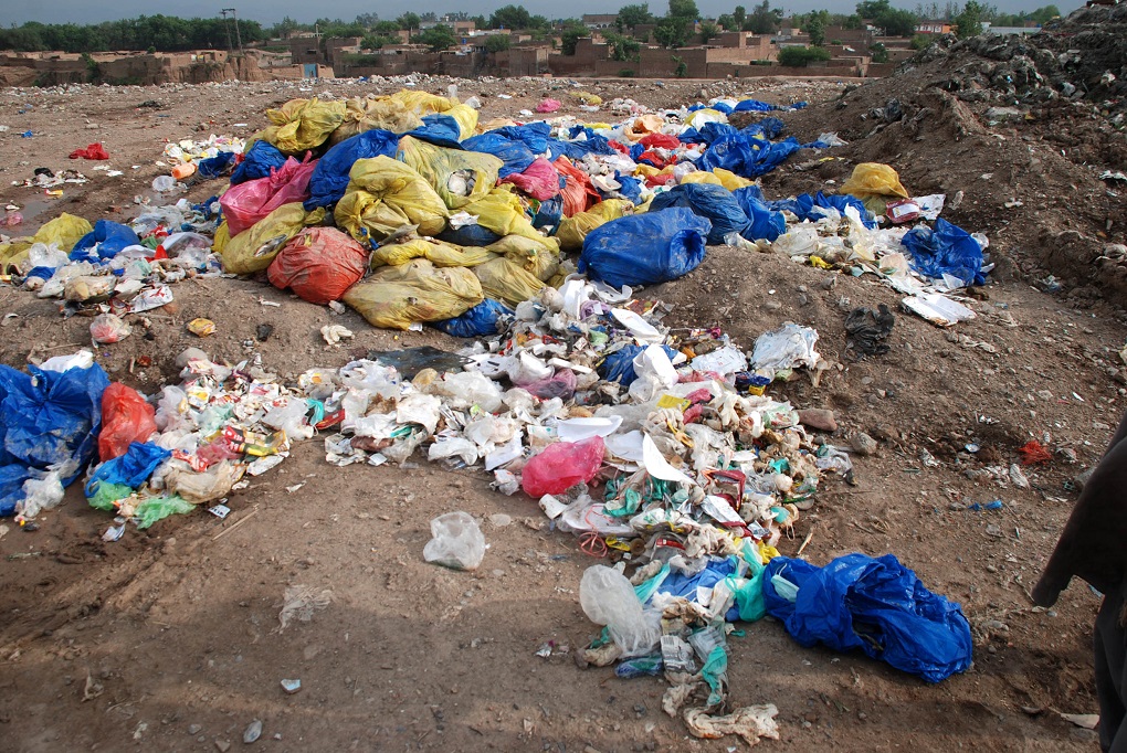 <p>Trash, including hospital waste, is lying in the open in Aftab Abad where dwellers have forcibly stopped WSSP from dumping of solid waste due to proximity of the site with population [image by: Adeel Saeed]</p>