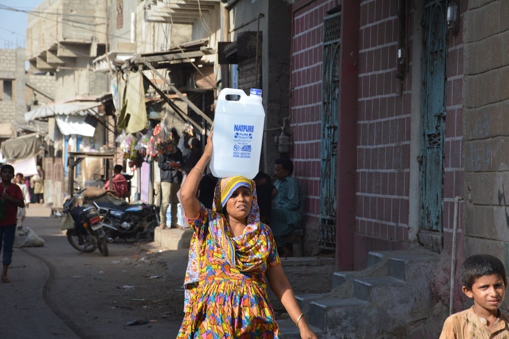 karachi slum during heatwave - woman carried bottle of water over her head