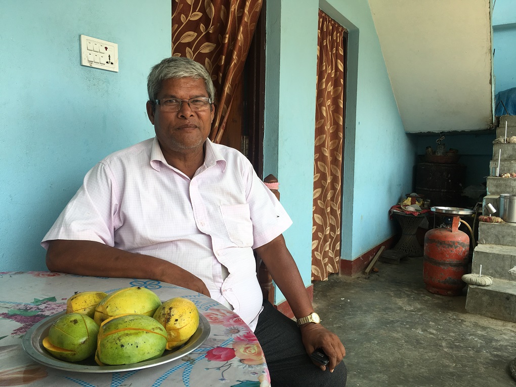 Surendra Prasad Chaudhary sitting down next to a fruit bowl