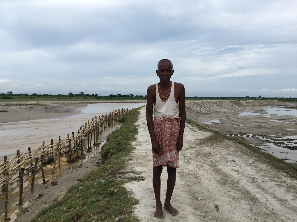 <p>A resident of Raghunathpur standing on an embankment with bamboo revetment on the Sundari river [image by: Peter Gill]</p>