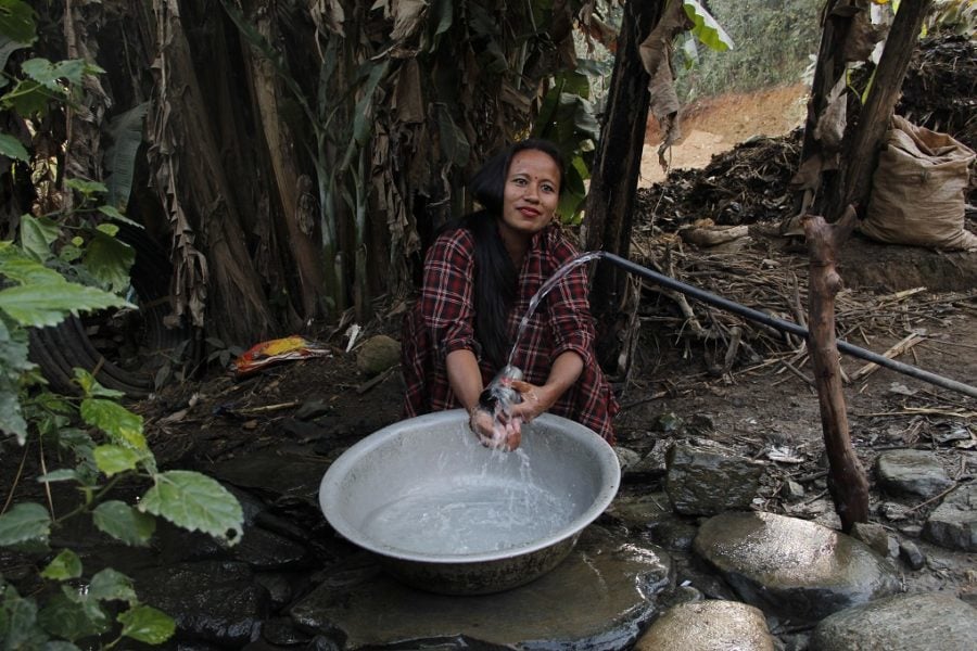 Sharada Bogati of Bidur-9 cleaning dishes beside her home. Unlike many neighbourhoods in Bidur, families in her neighbourhood get enough water for their daily use and also for vegetable farming [image by: Bhrikuti Rai]
