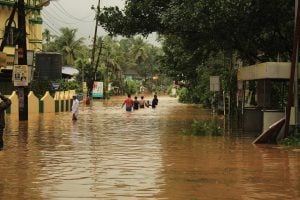 <p>Residents wading through water after the 2018 Kerala floods (Image source: Adeeb Mohammed/Alamy)</p>