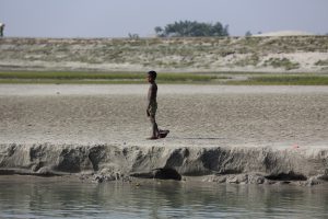 boy walking along the banks of Bangladesh made up of silt