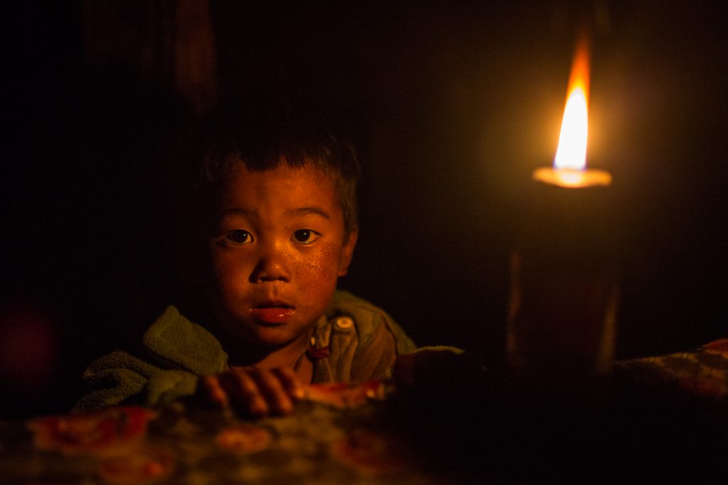 A boy with Kerosene lamp in his house in Tumkot village, Humla district of Nepal [image by: Nabin Baral]