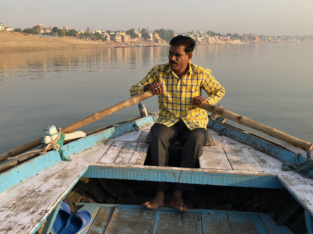 man rows in a polluted Ganga