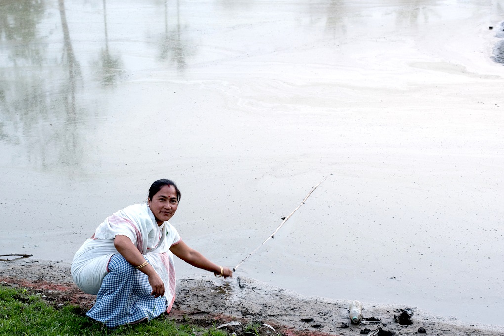 Barnali Taid sits next to what was her paddy farm and is now a permanent pond due to siltation from floods, near her house in Joinpur 