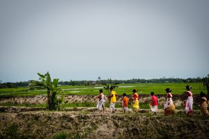 Children crossing the flood-impacted barren paddy fields of North Lakhimpur