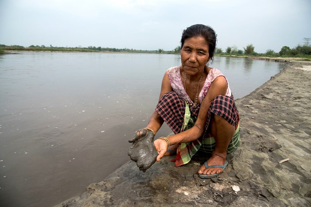 Bisan Narah showing the high concentration of silt in the red river of India with her hands