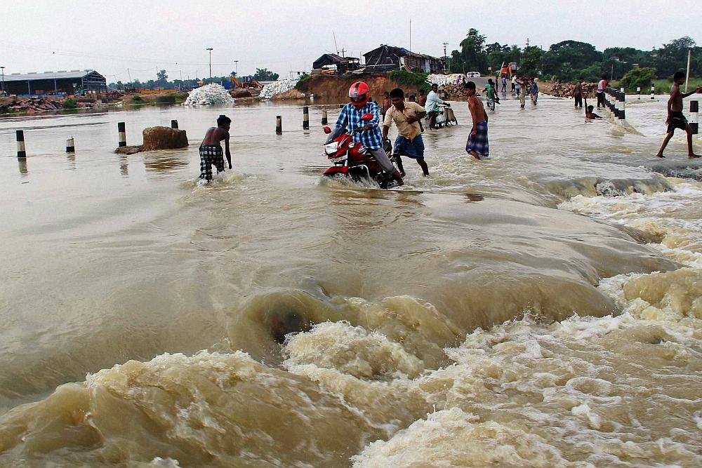 Villagers in Norjai Setu in Burdwan district of West Bengal try and navigate the flooded road