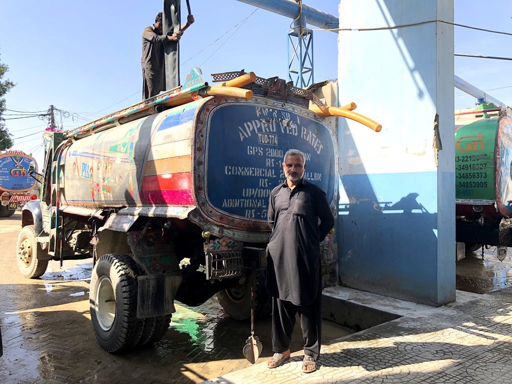man in front of four h2o water tankers in Karachi 