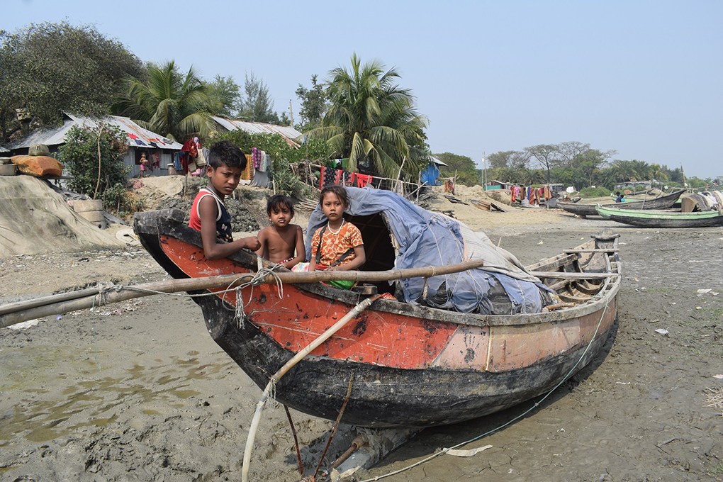 three children sit in an anchored fishing boat in Jaladash