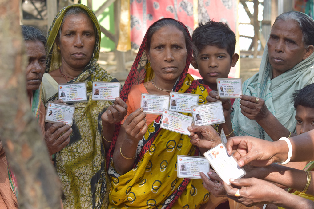 women in Char Gaze in Ramgati holding up their National Identity cards that recognise them as citizens of Bangladesh