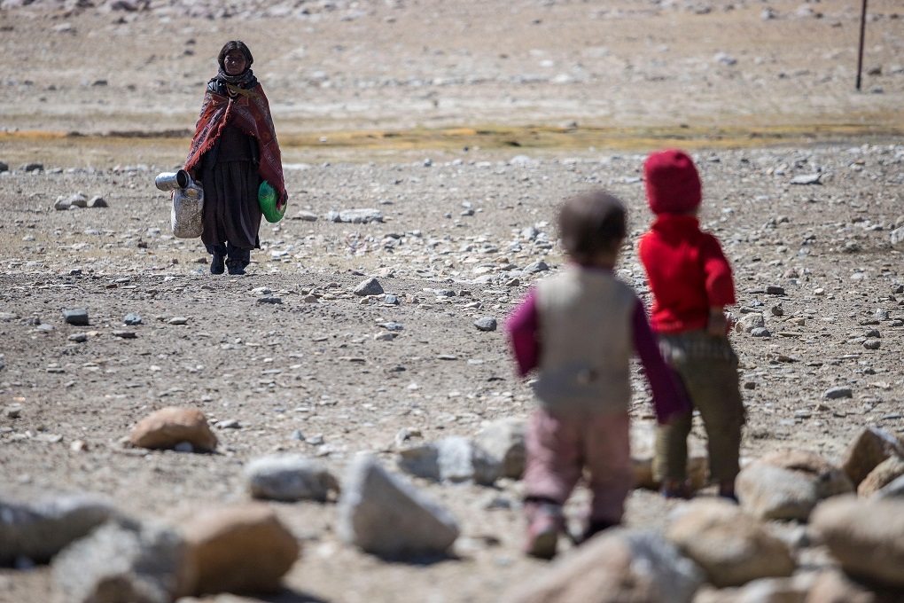 two children waiting for woman returning from collecting water in Ladakh