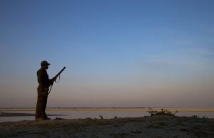 Forest guard armed with rifle, looking out over Brahmaputra River, Kaziranga N.P., Assam, India, January