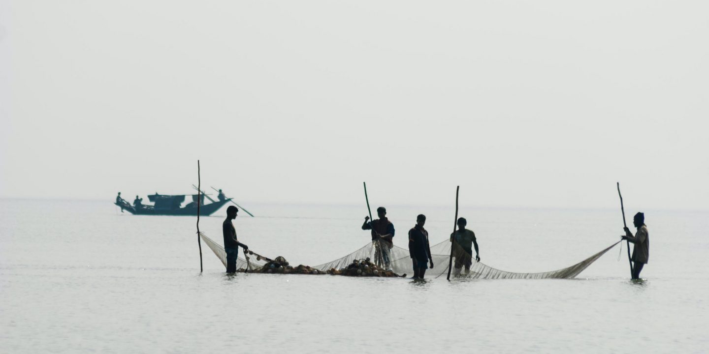 Five fishermen holding a net against the skyline in Bangladesh portion of Bay of Bengal