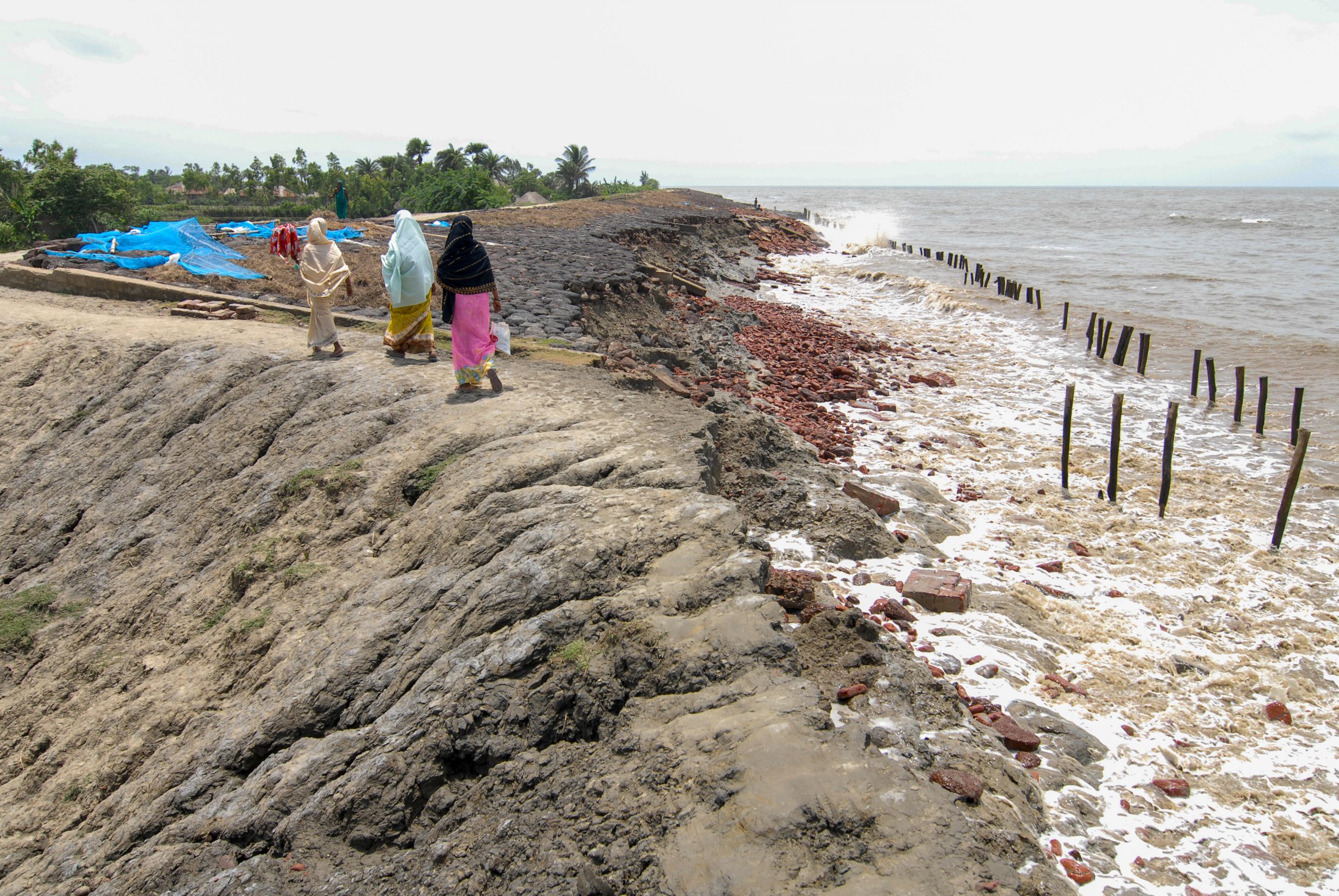 Women walk along Sundarbans embankments with broken dyke due to sea erosion