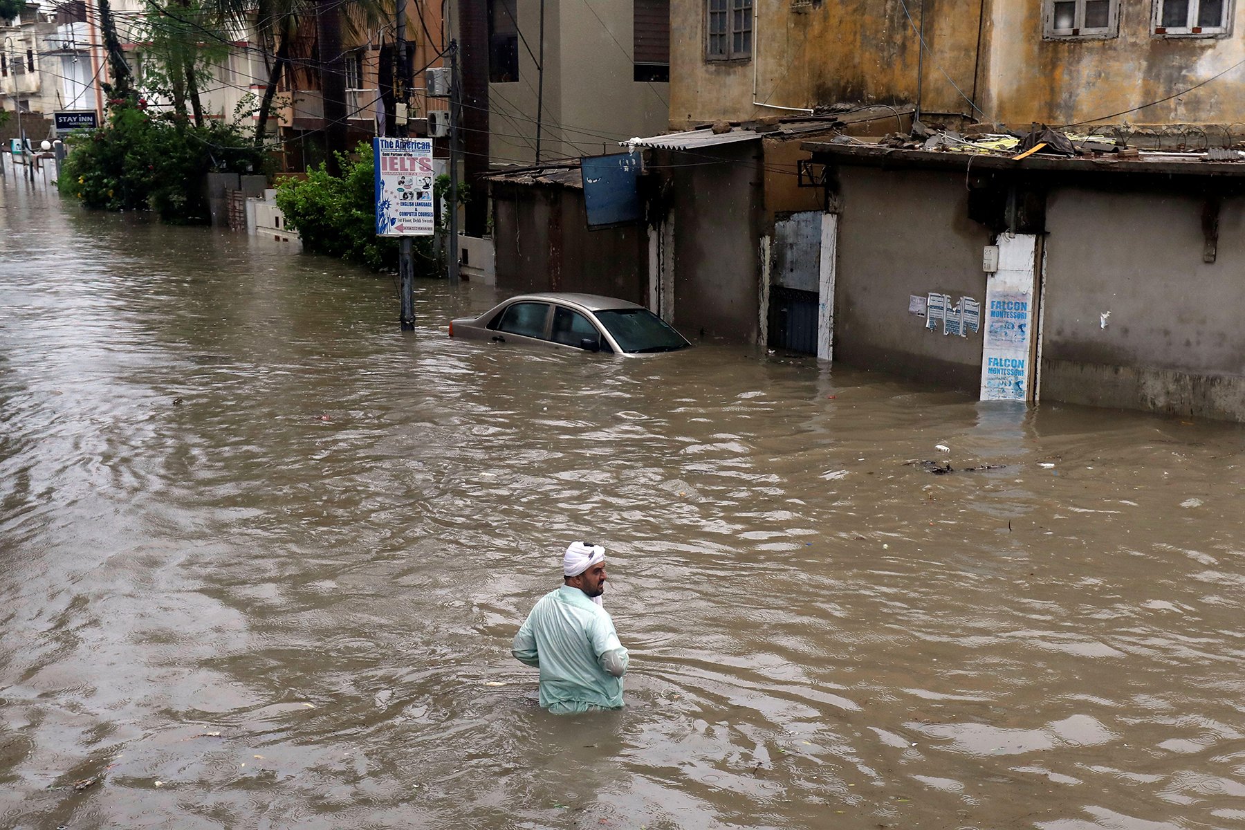 A man wades through the Karachi flood street with submerged vehicle during monsoon rain, as the outbreak of the coronavirus disease (COVID-19) continues, in Karachi, Pakistan August 27, 2020. REUTERS/Akhtar Soomro