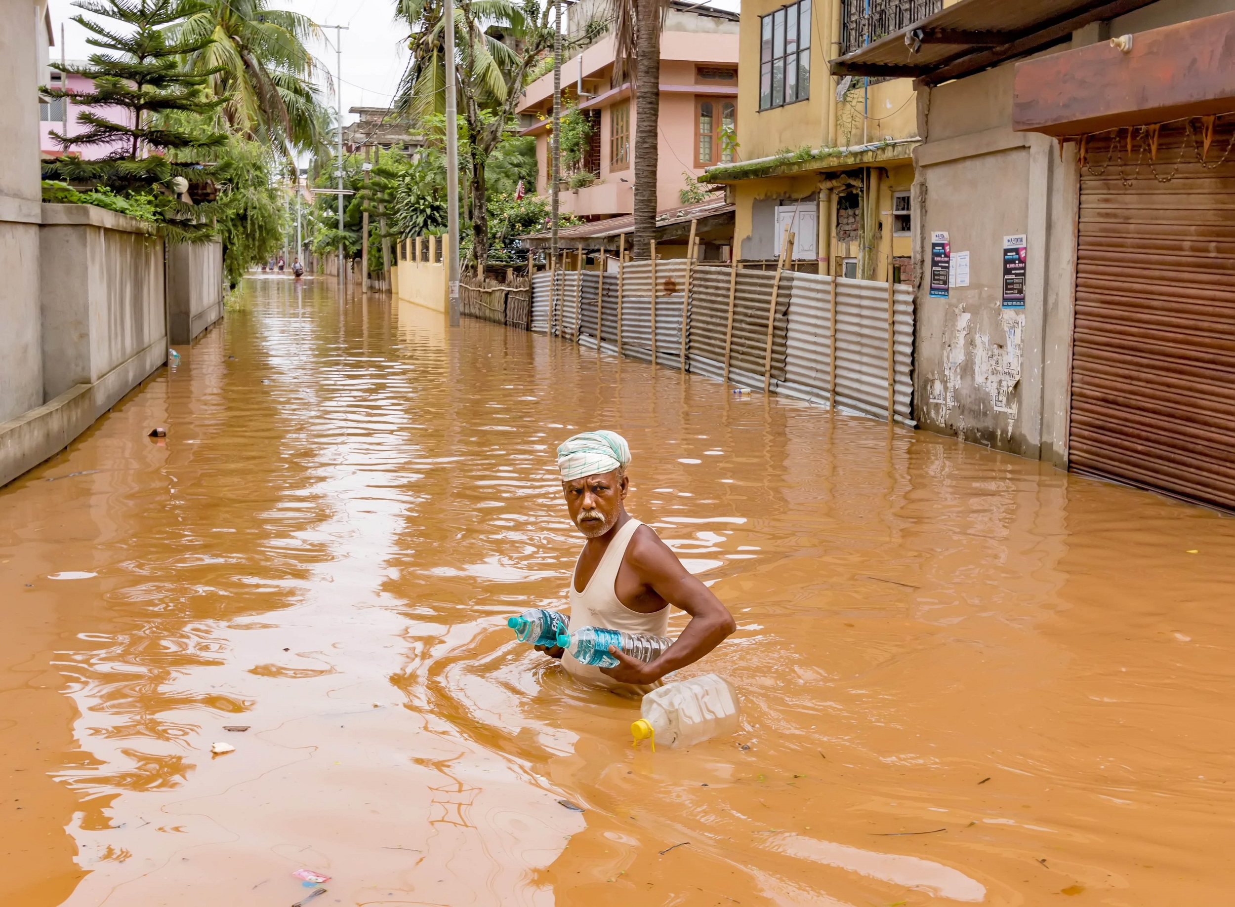 <p>An man carries bottles of drinking water to his home, which were provided by the relief team during flooding on July 7, 2016 at Anil Nagar, Guwahati [image: Vikramjit Kakati India/ZUMA Wire/Alamy Live News]</p>