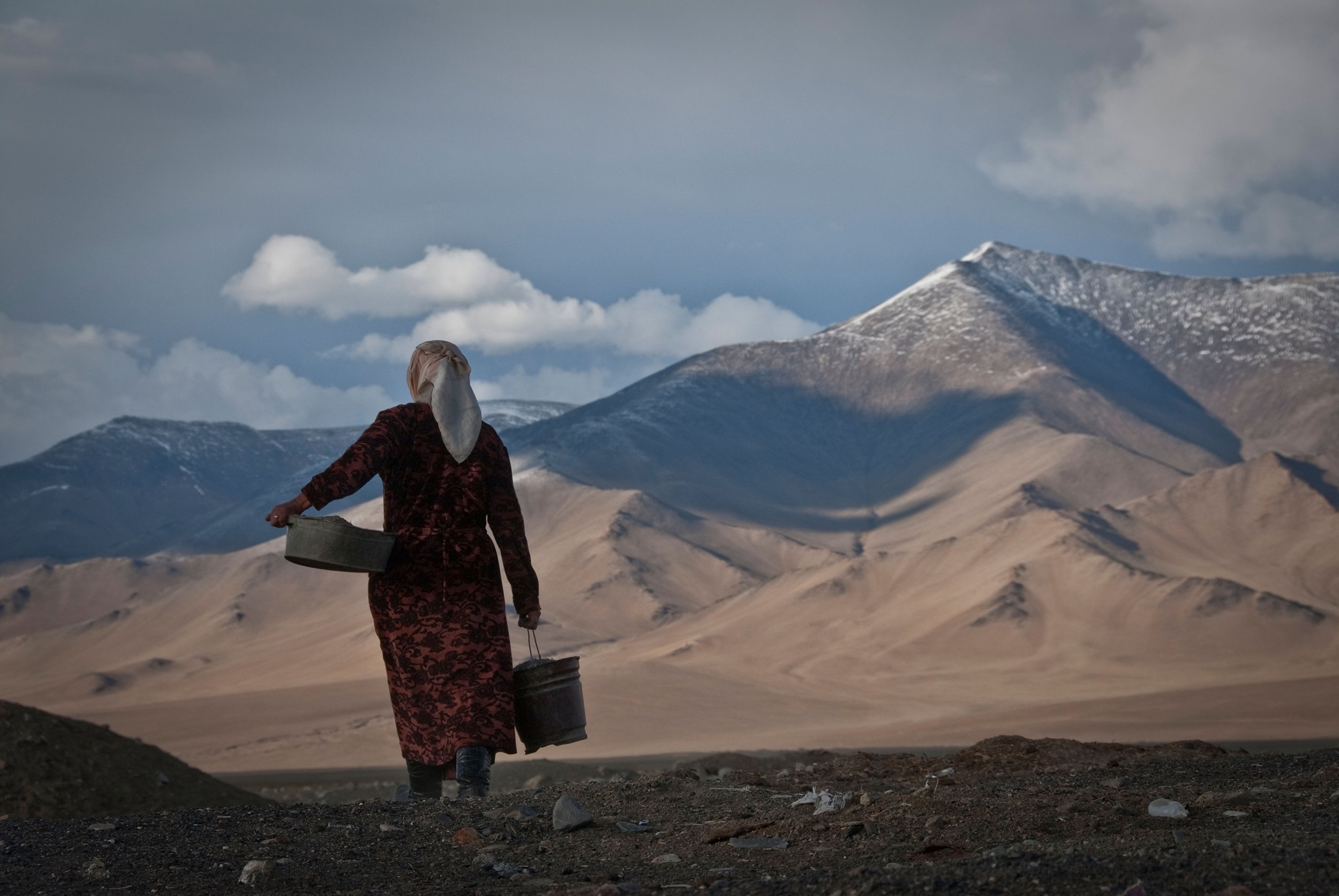 Woman carrying water from Karakul Lake in Tajikistan [Image by: Alamy]