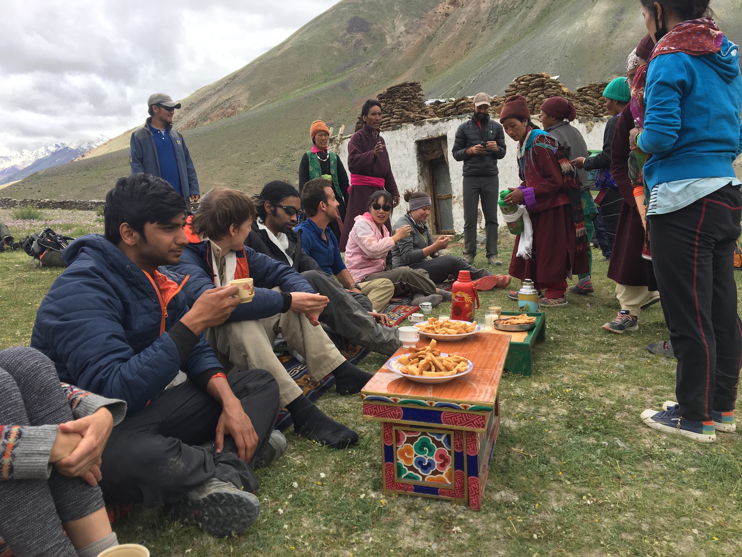Global Himalayan Expedition team eat snacks with community (photo credit: GHE)