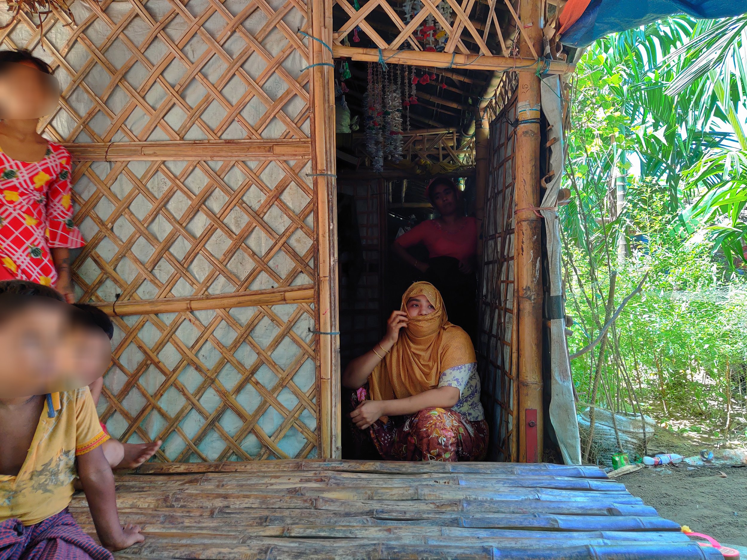After making three futile attempts to reach Malaysia, Sabikunnisa at the doorway of the shack she shares with her brother and his family in a Rohingya refugee camp near Teknaf. Some faces have been blurred to prevent possible retaliation by human traffickers 