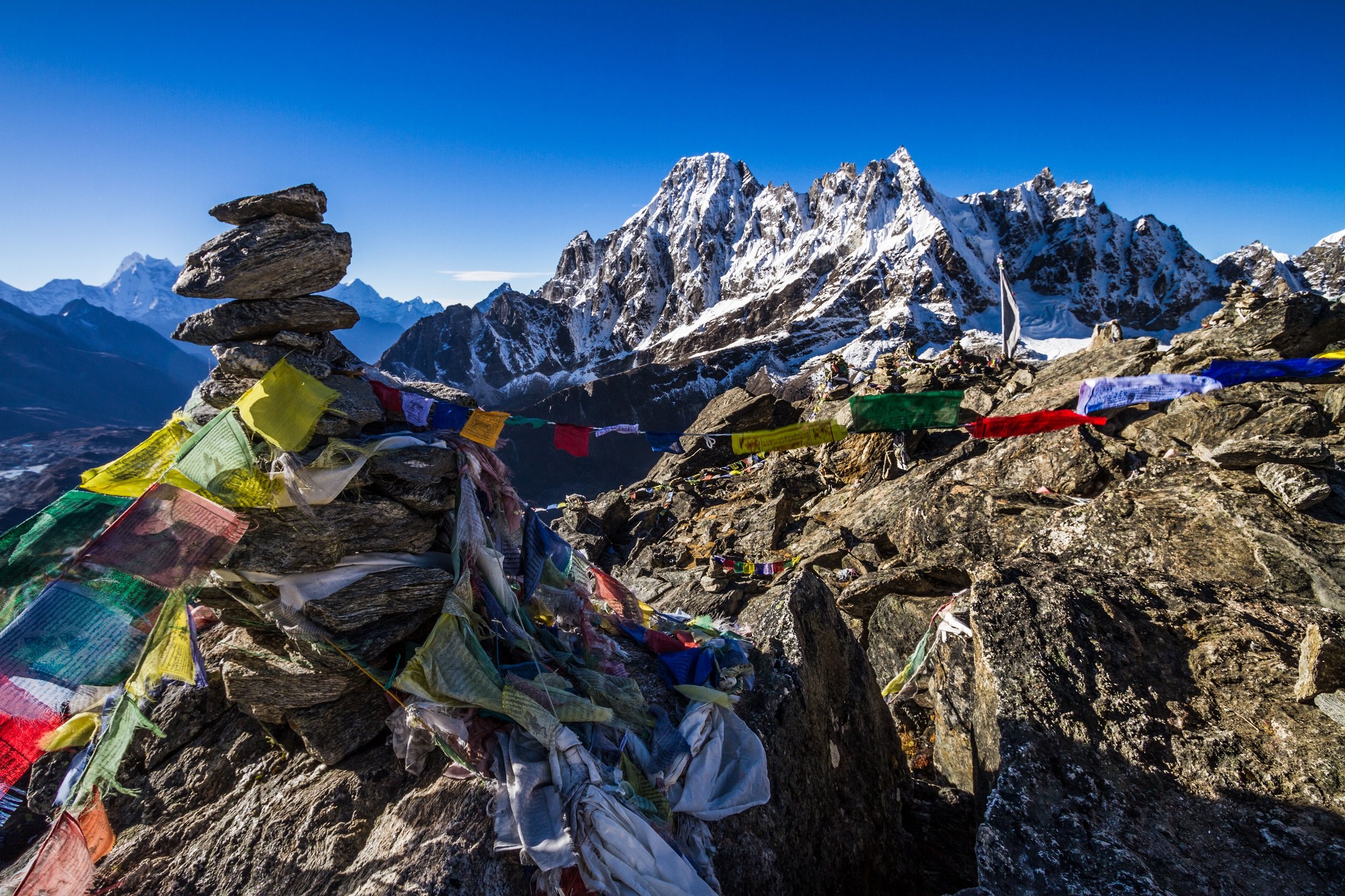<p>Prayer flags and the Machermo Range from Gokyo Ri, Nepal [image by: Peter Carey / Alamy]</p>