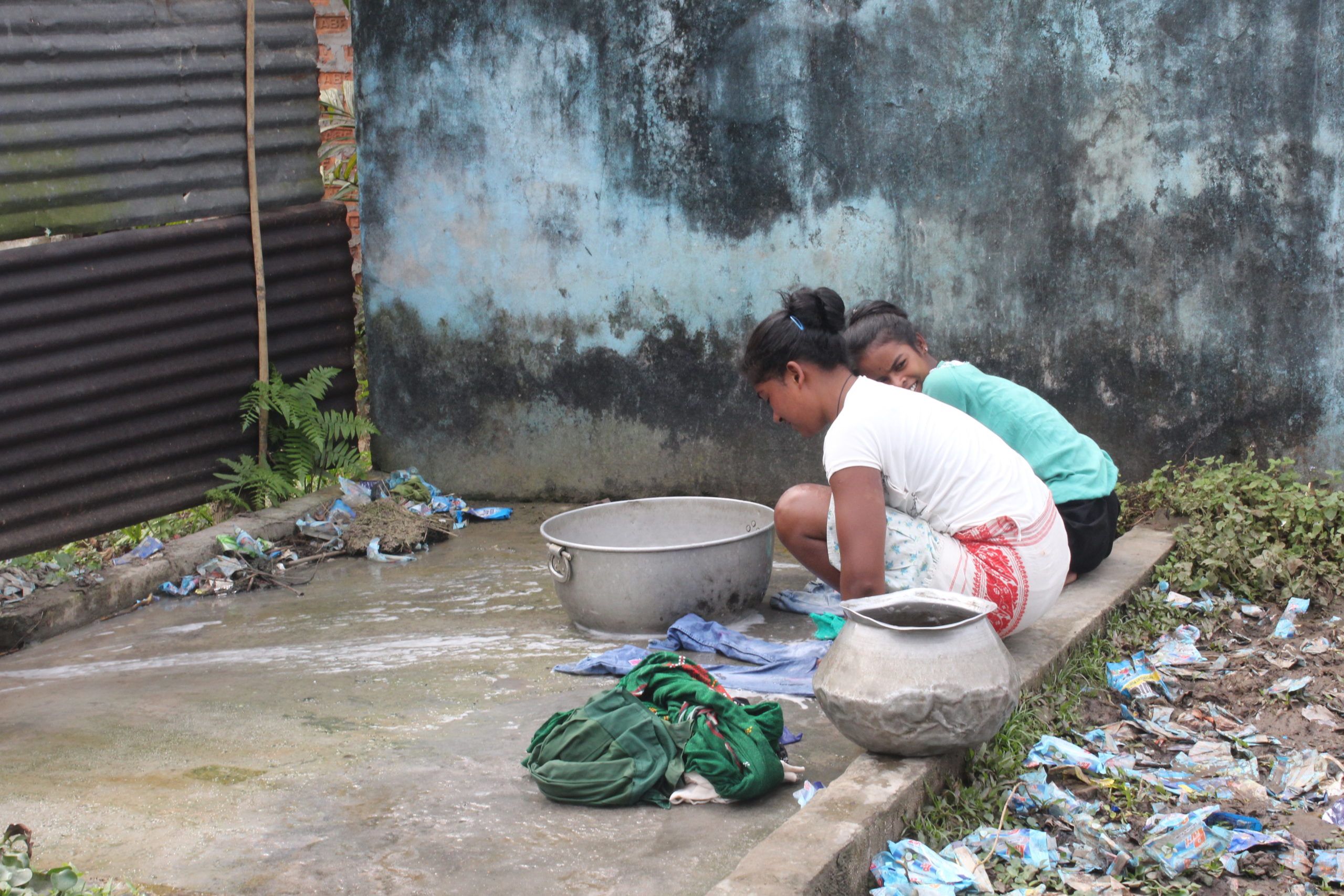 Girls wash clothes on a platform close to the pond in Letekujan, Assam, India, Sanskrita Bharadwaj