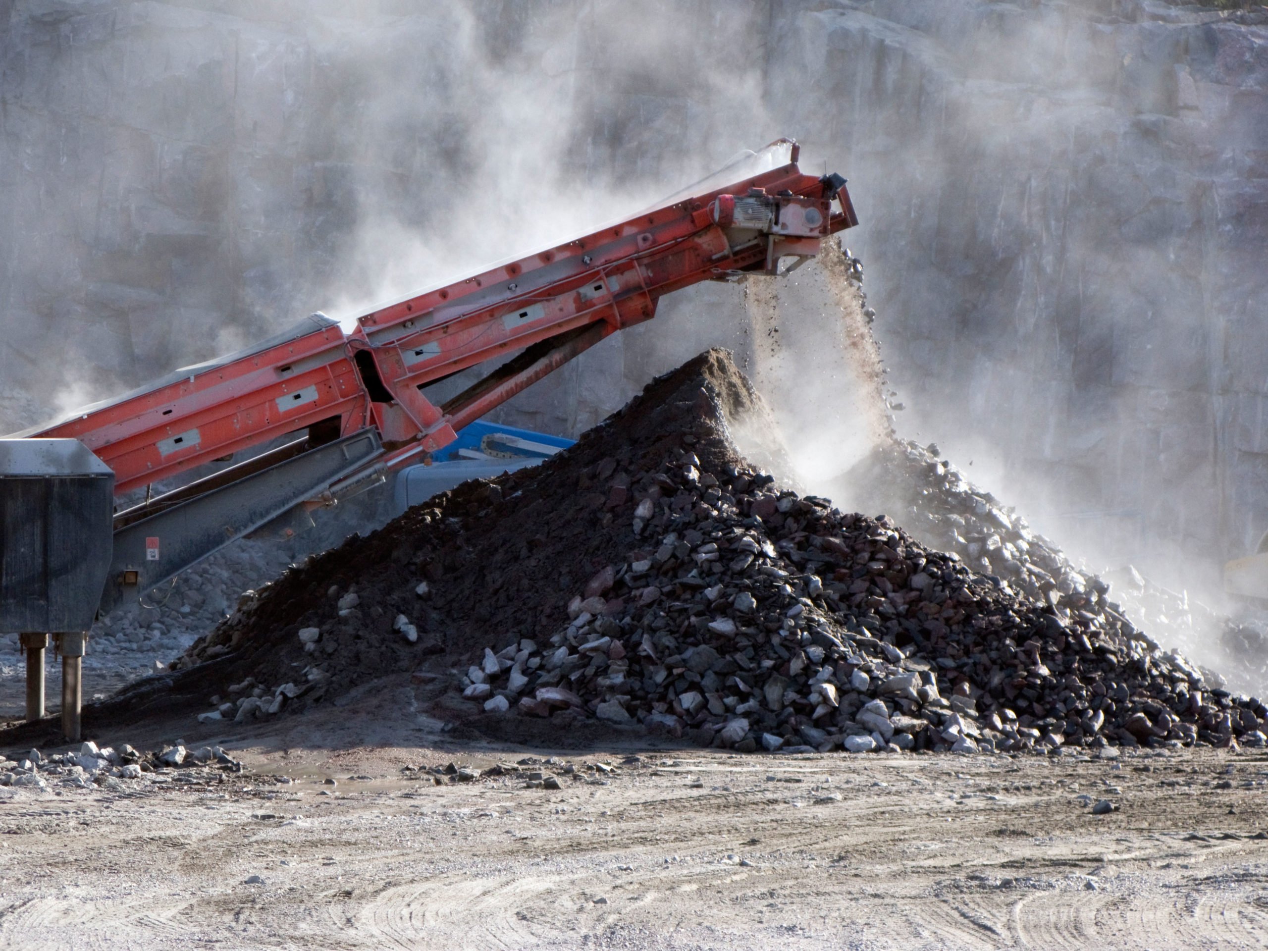 Crushed stones pile up below a conveyor belt from a stone crusher