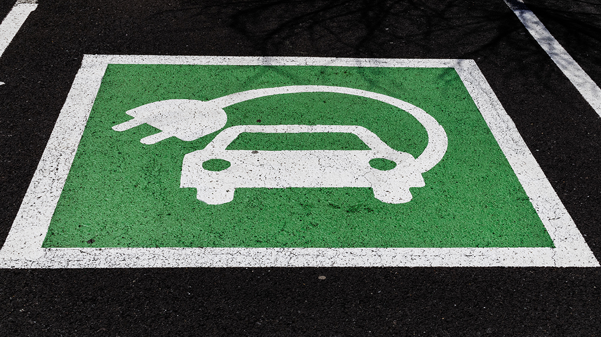 Green electric vehicle parking sign, painted on asphalt
