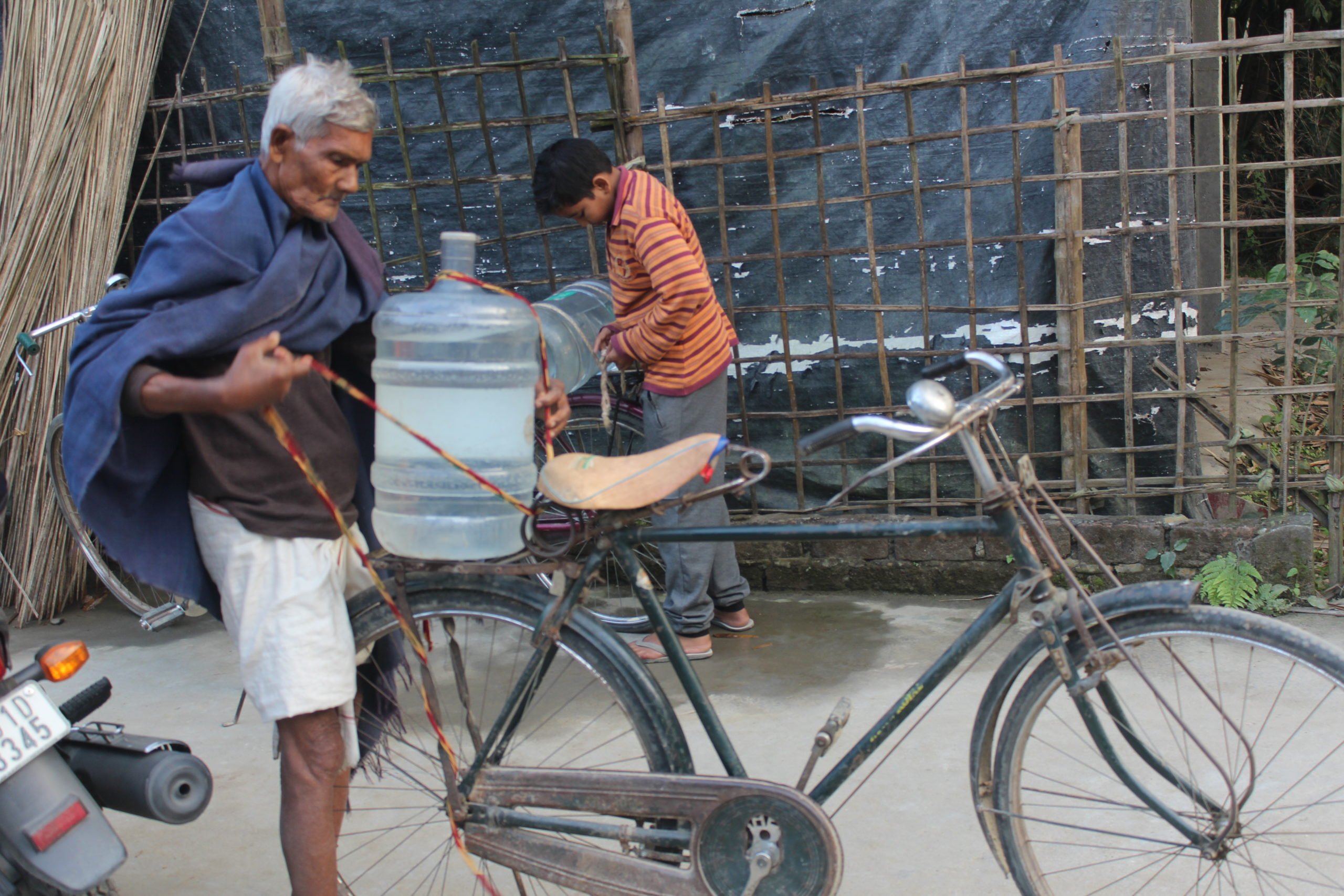 Villagers strap filled water containers onto their bikes, Jitu Kalita, GVM