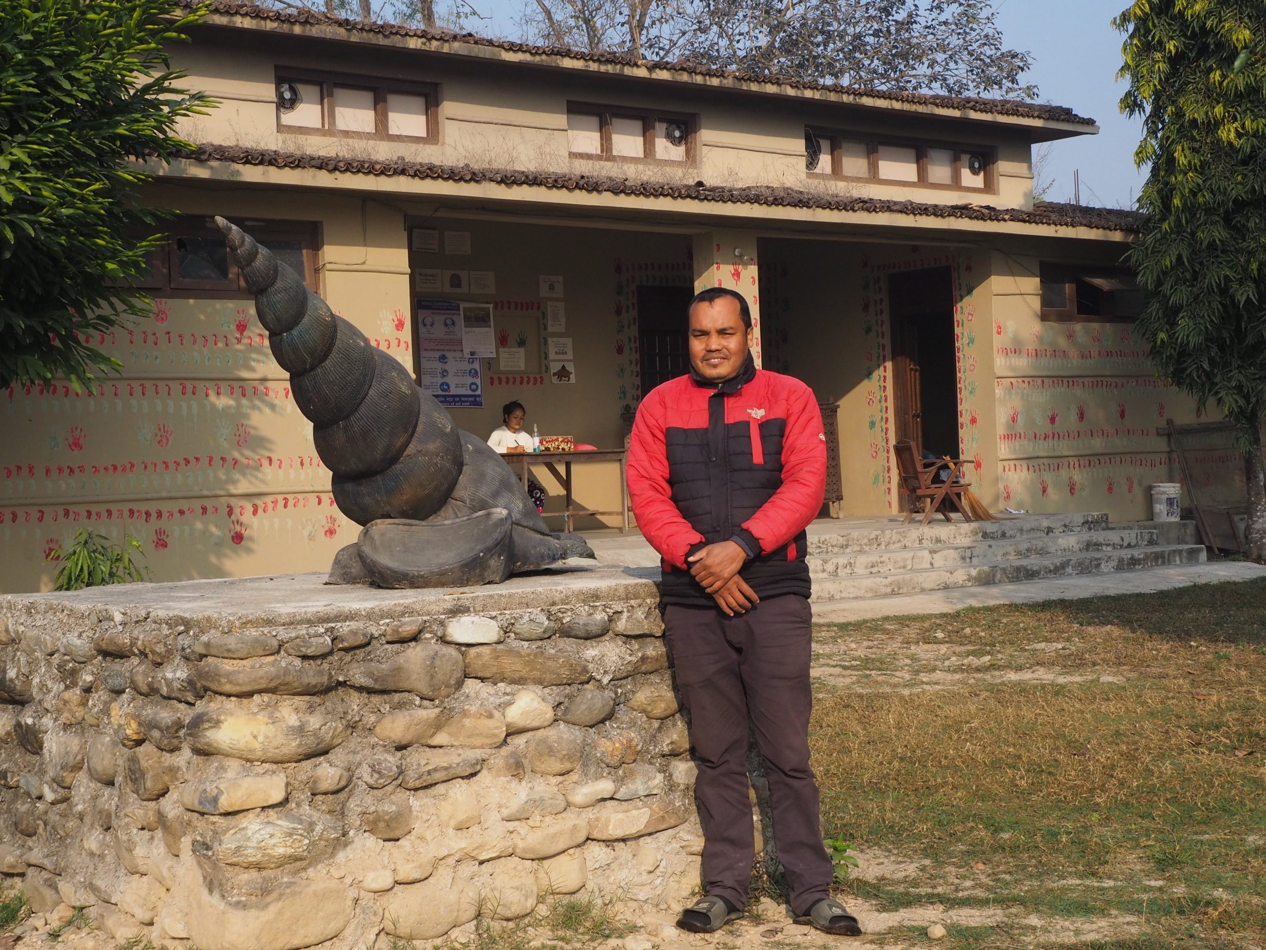 Birendra Mahato next to a statue of a ghongi (water snail, a traditional indigenous food) at the Tharu Cultural Museum and Research Center outside Sauraha (Image: Peter Gill)