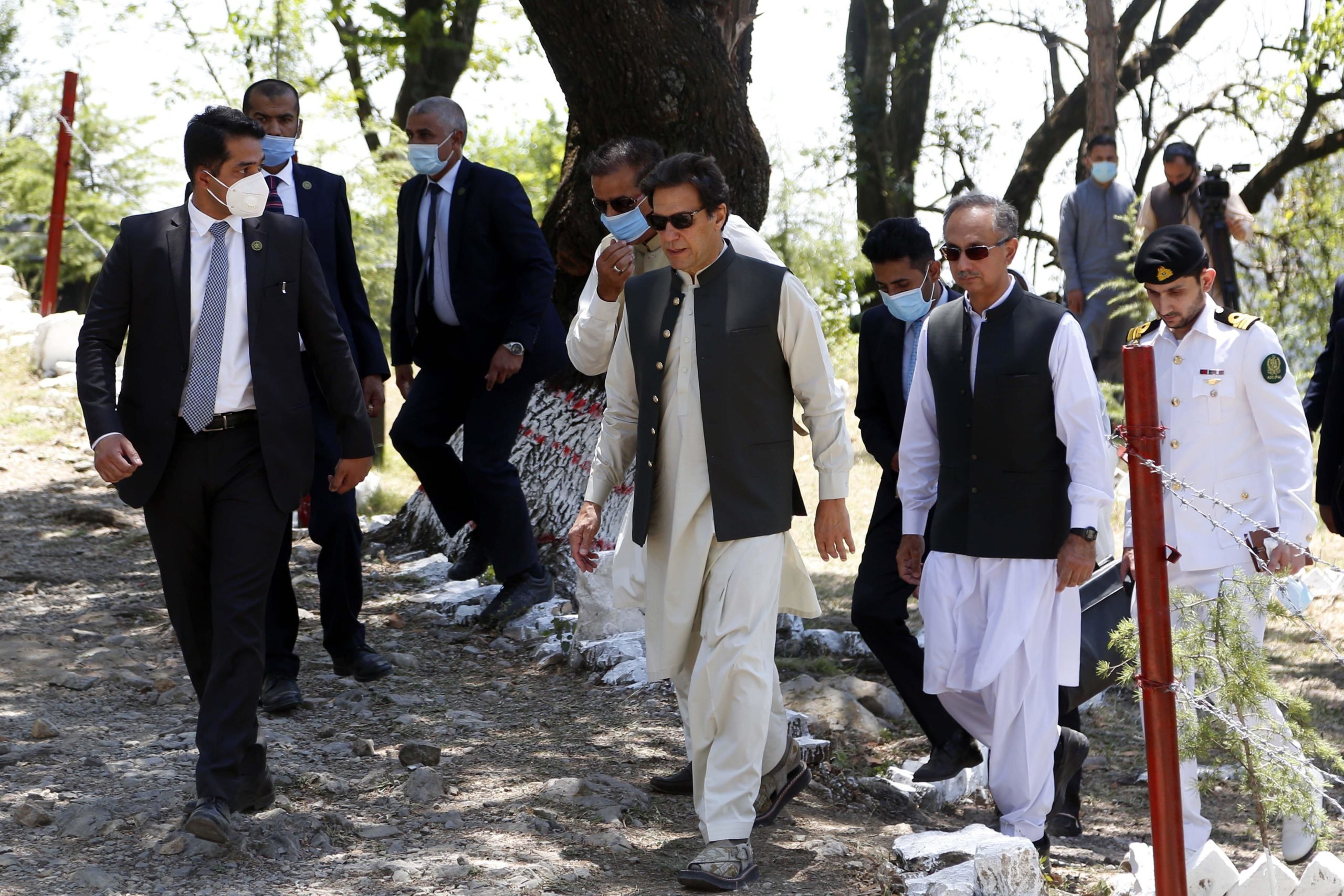Pakistani Prime Minister Imran Khan (C) returns from where he planted a tree during an event in connection with the 10 Billion Tree Tsunami program in the country's northwest city of Haripur on May 27, 2021