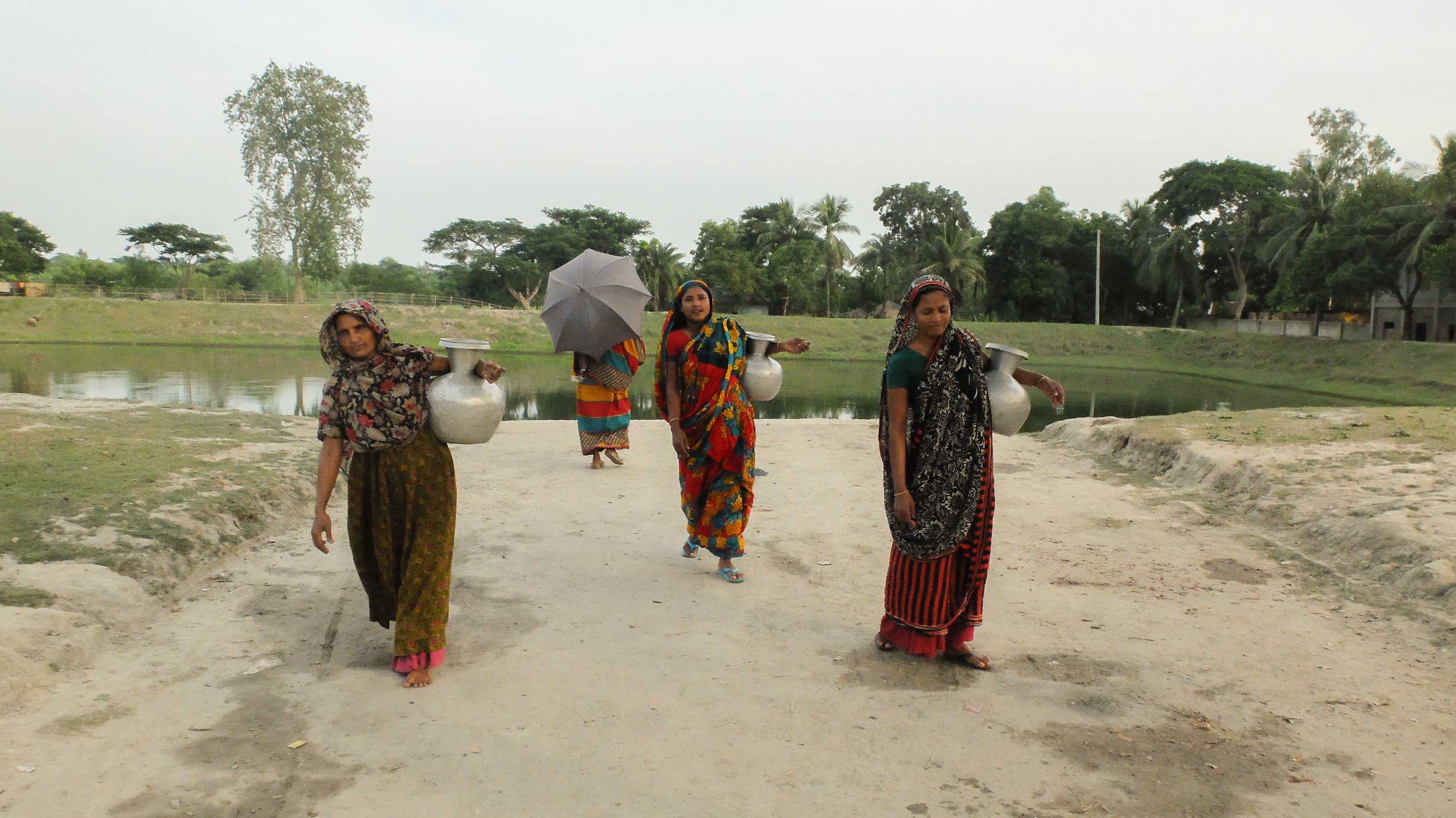 Womenfolks in rural Bangladesh returning home after collecting water from a pond