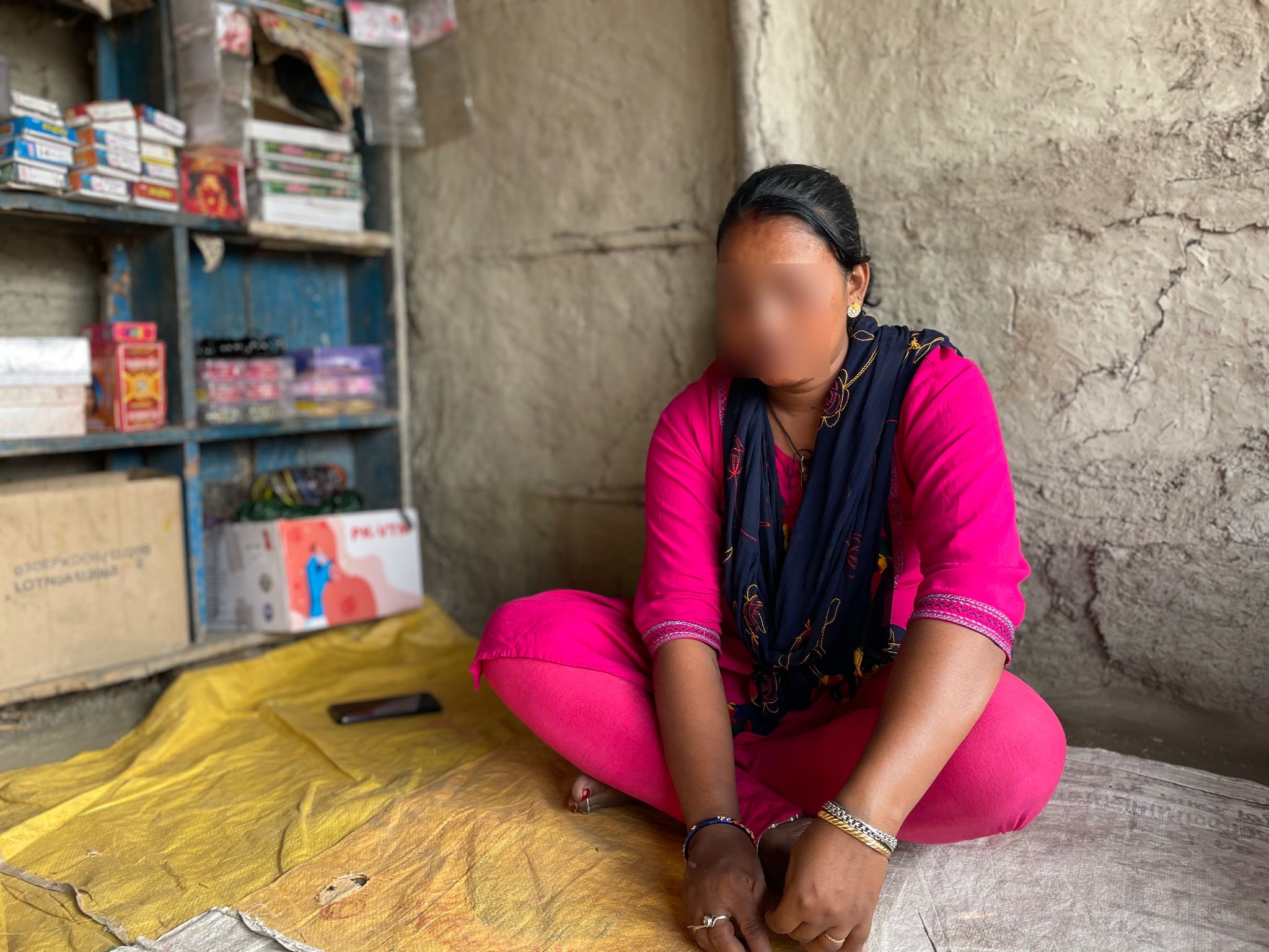 Pritha Devi (pseudonym), sat crossed legged in pink clothing. Face blurred to protect her identity