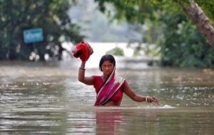 A woman wades through a flooded village in the eastern state of Bihar, India