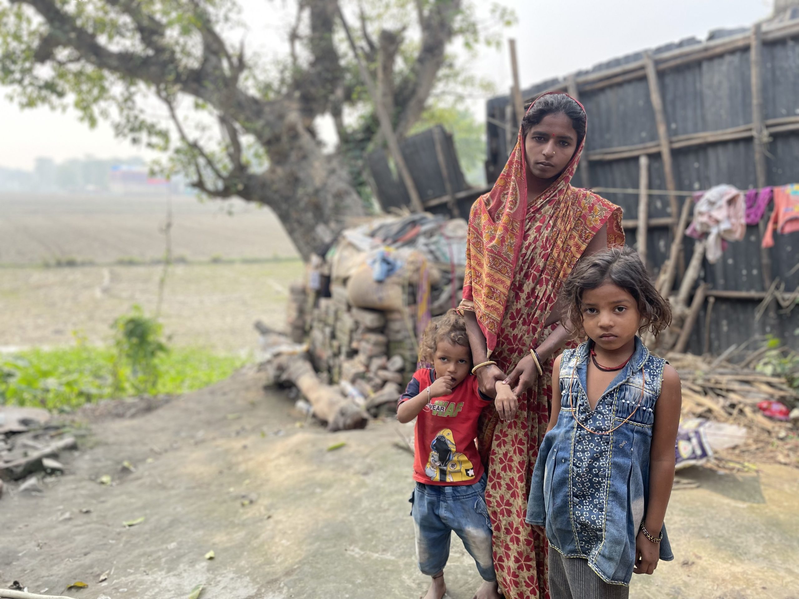 Ravina Devi, whose husband died in the 2020 floods, stands behind her two daughters