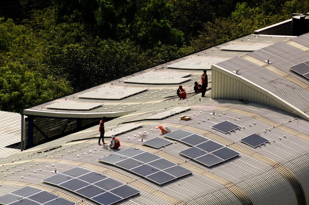 Workers install solar panels on the roof of a metro station, Amlan Mathur